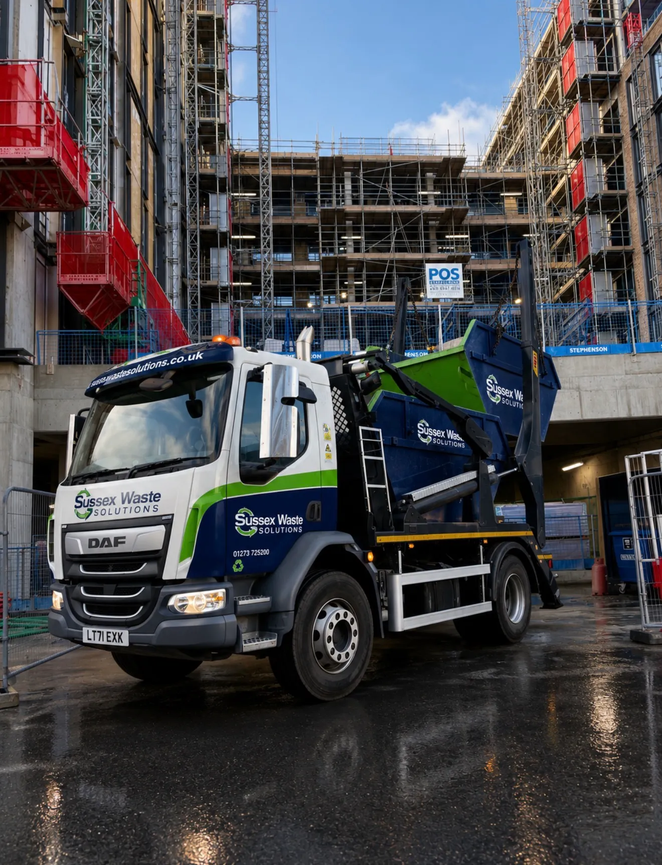 Sussex Waste Solutions truck parked at a construction site with scaffolding and building materials.